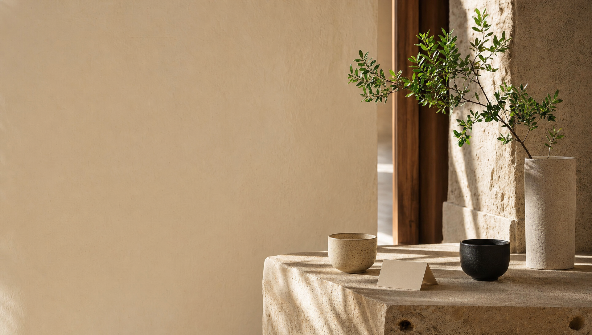 Calm architectural contact scene with warm stone, table objects and soft natural light